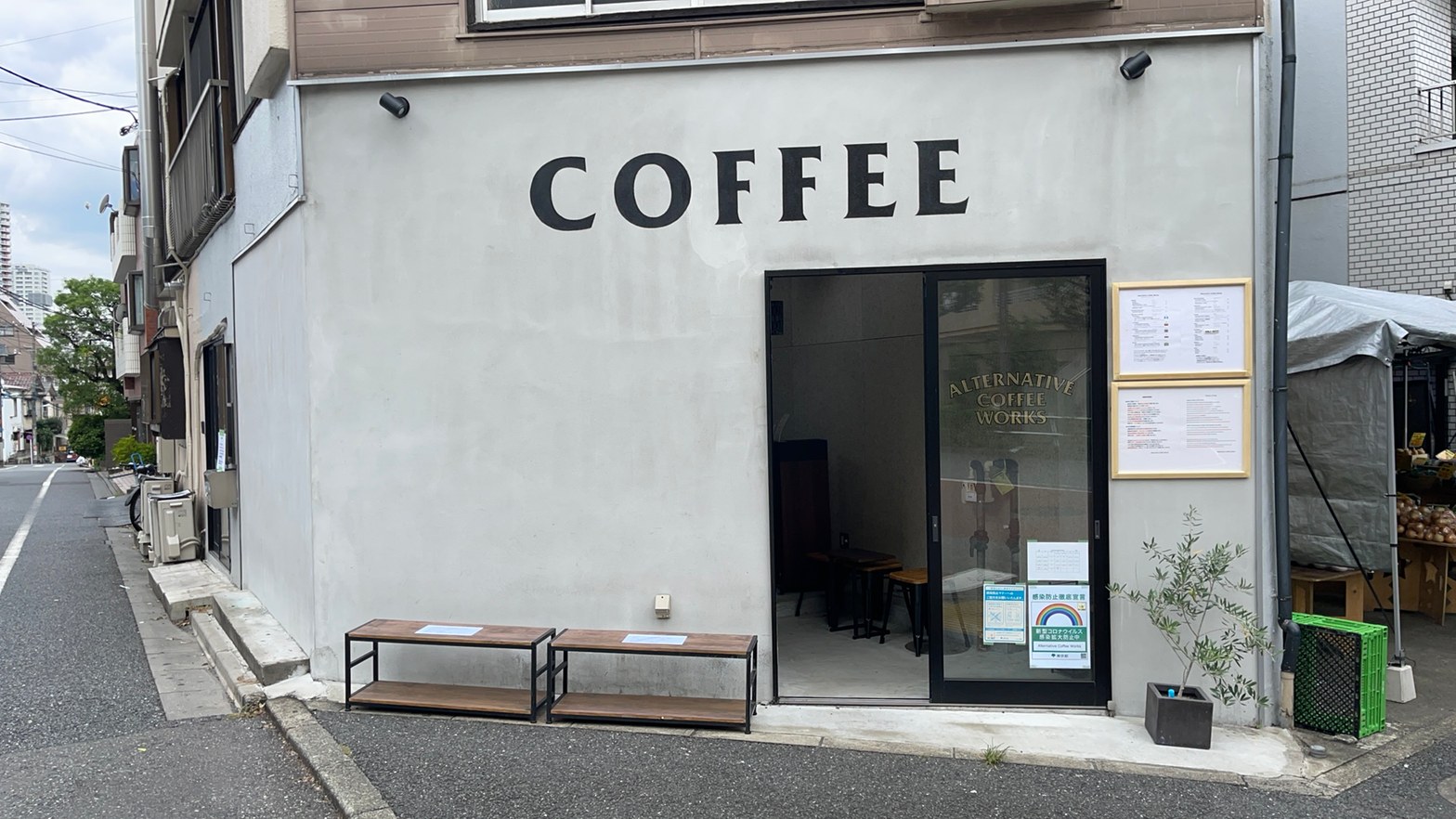 白い左官壁に大きく「COFFEE」と書かれた外観と、鉄脚の木天板ベンチ2台が並ぶ入口。